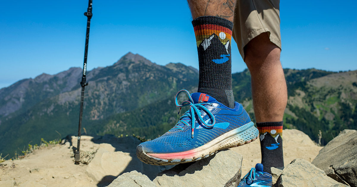 A man in mountain-themed wool hiking socks hikes a mountain trail in Port Angeles, Wash.