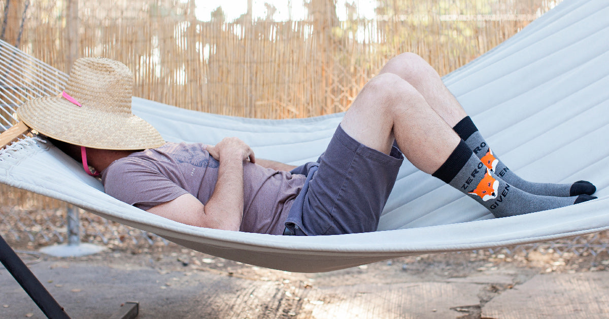 A man lays on a hammock wearing "Zero Fox Given" men's socks