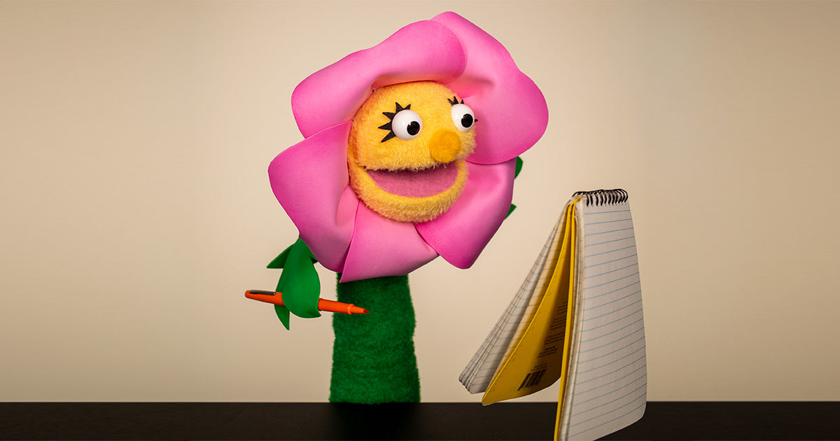 A cute flower sock puppet makes a list in a notebook
