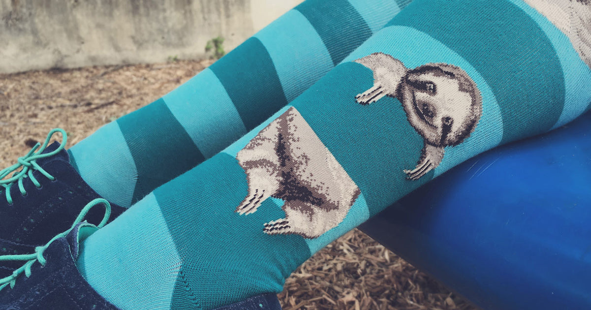 Sloth knee-high socks for women with cute sloths hanging on teal stripes.