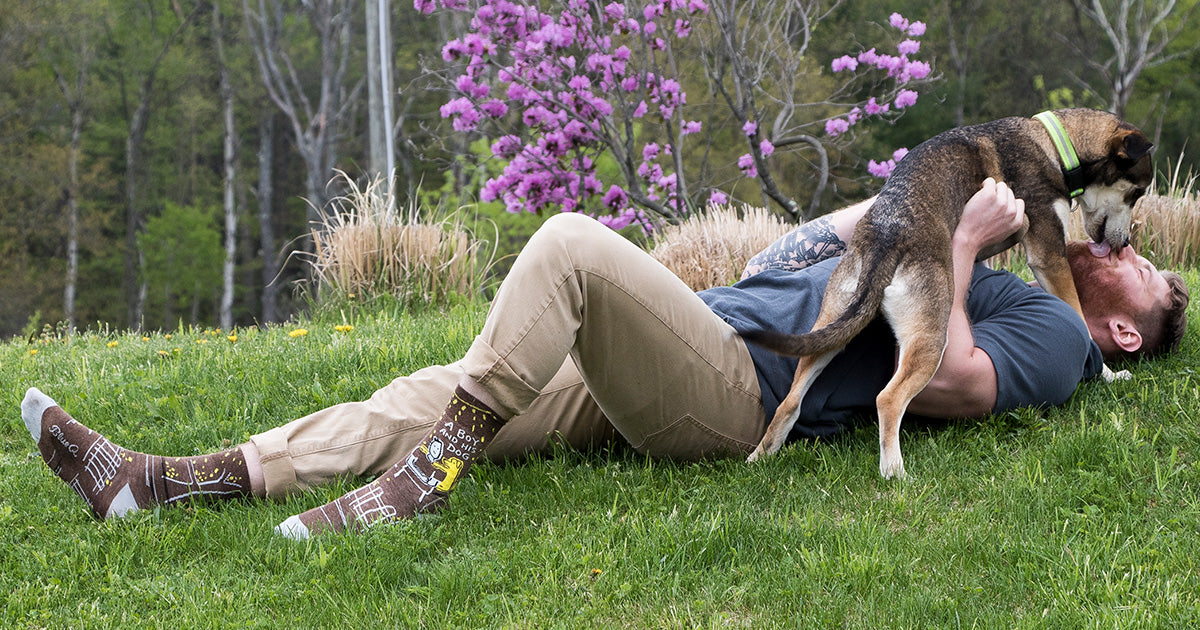 A man plays with his dog while wearing fun novelty socks with dogs on them.