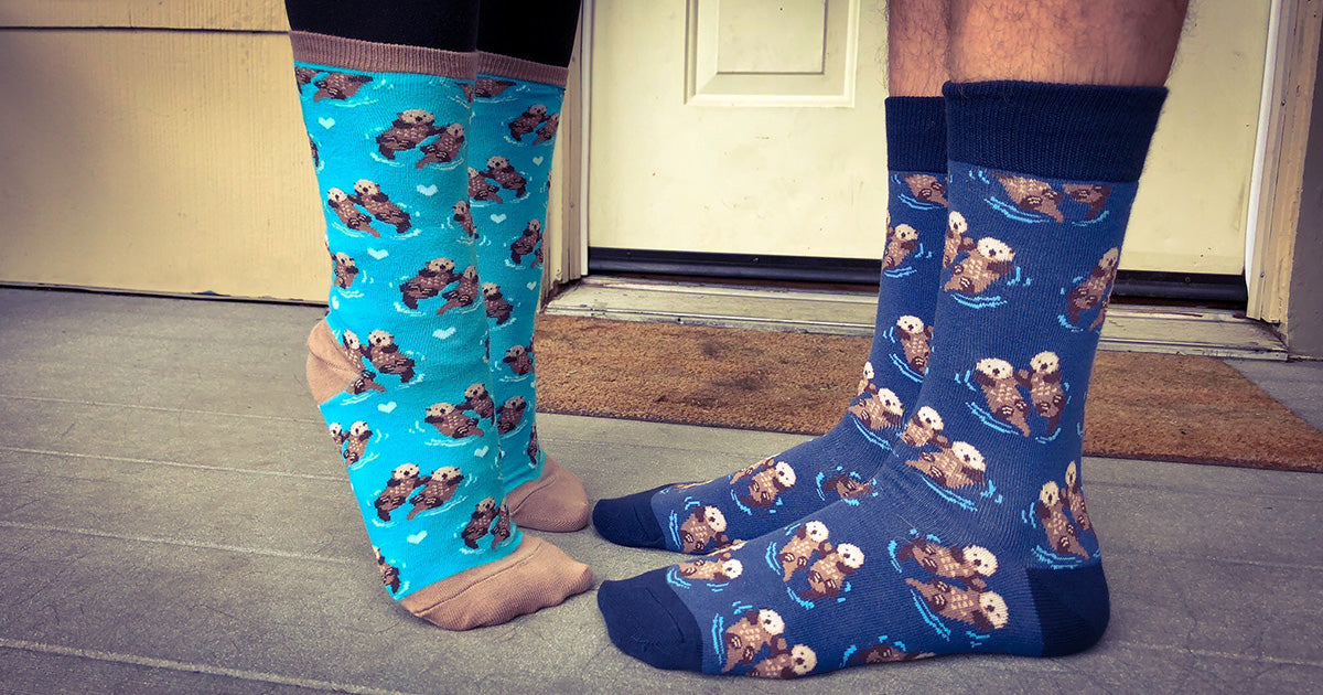 Matching otter socks for men and women worn by two models.