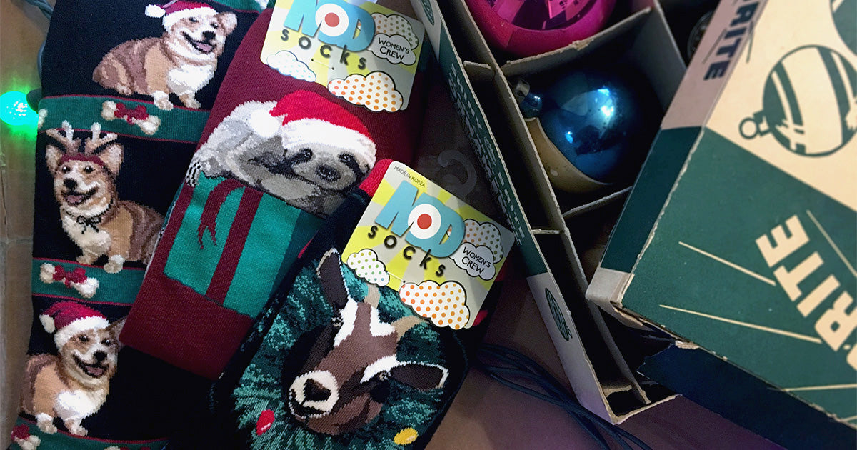 Christmas socks with animal designs featuring corgi dogs, Santa sloths and goats with Christmas lights.