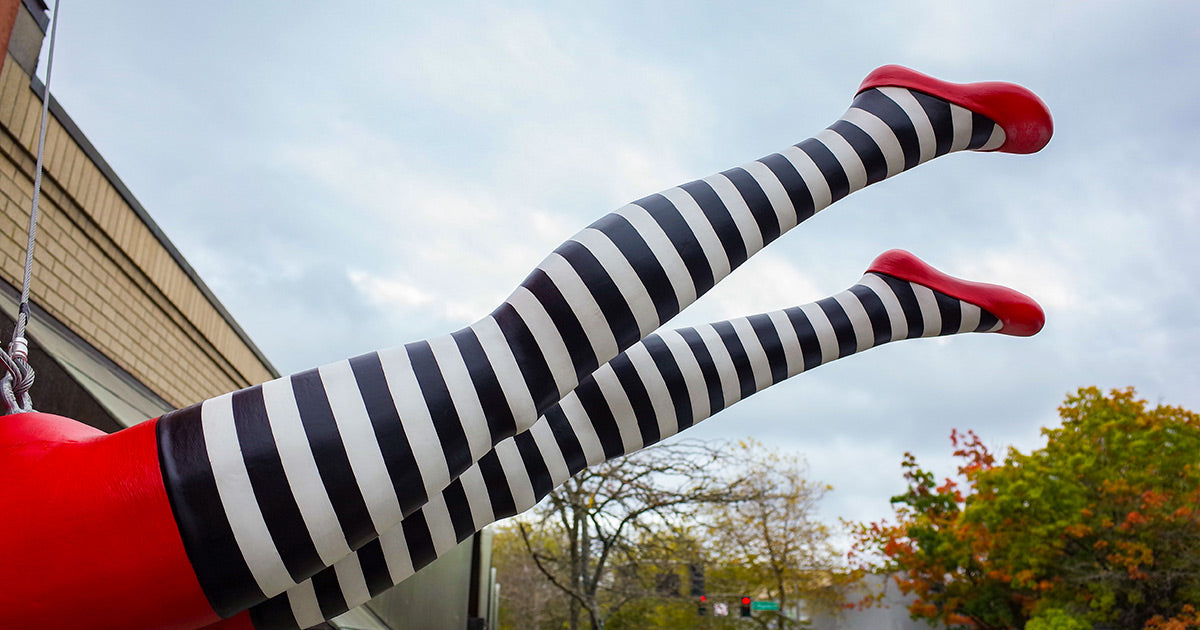 The exterior of Cute But Crazy Socks and the black and white striped legs of our trapeze artist sculpture that hangs above our door.