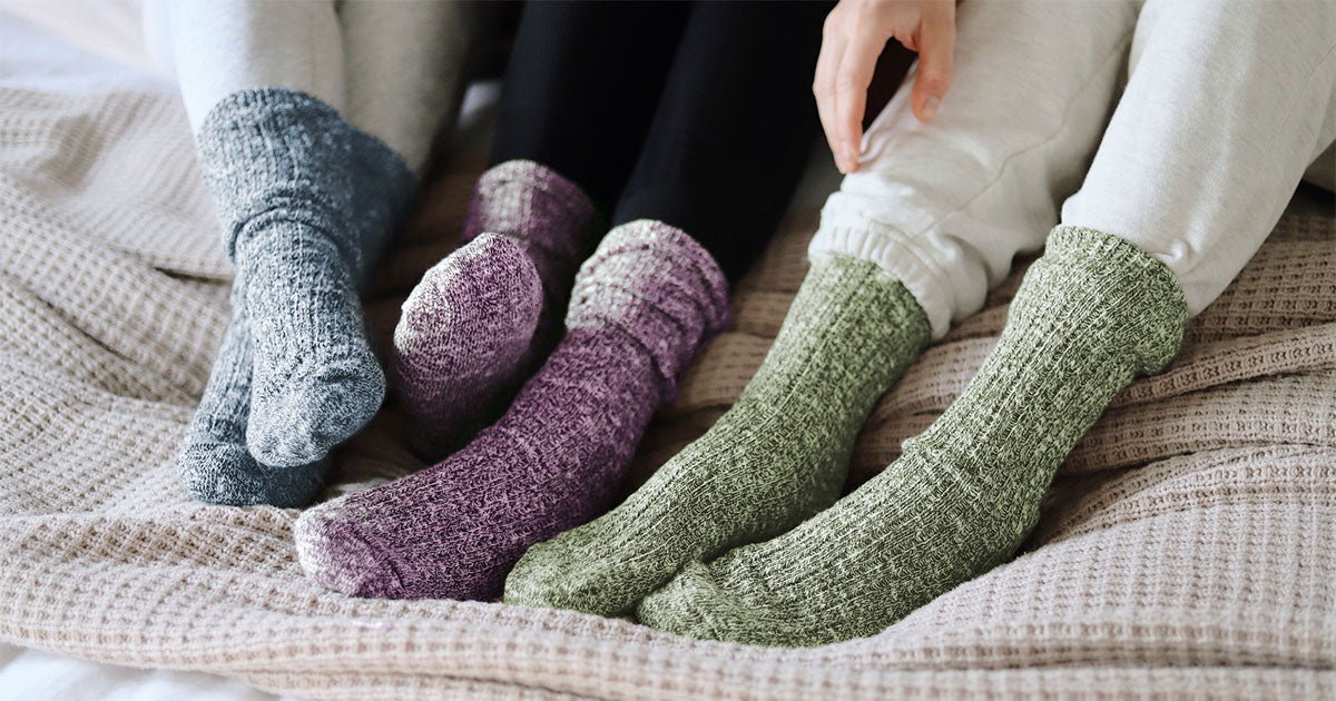 Three people wearing cozy slouched slub-knit crew socks in bed.