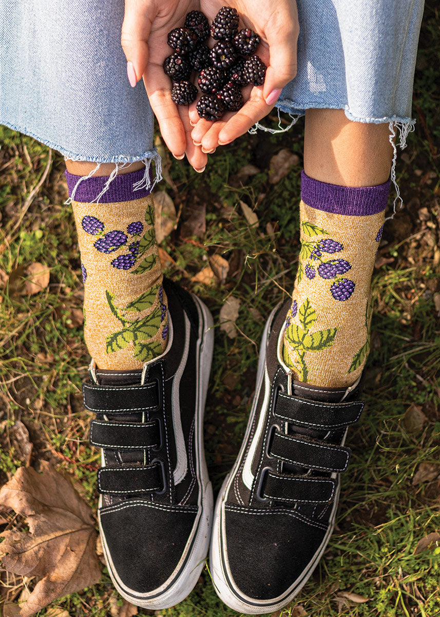 Tan crew socks feature a motif of blackberries and brambles, with dark purple accents at the heel, toe and cuff.