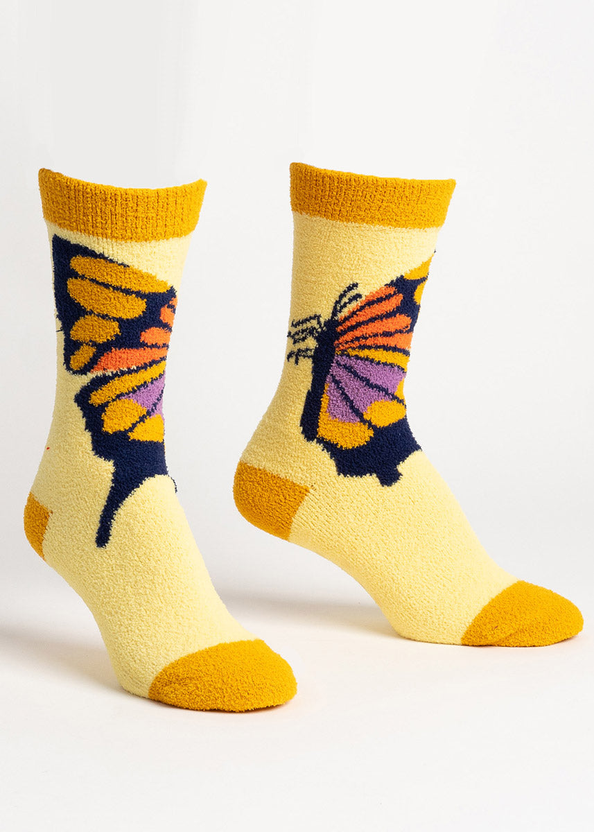 Fuzzy yellow slipper socks for women with a yellow, orange, and purple butterfly on them.