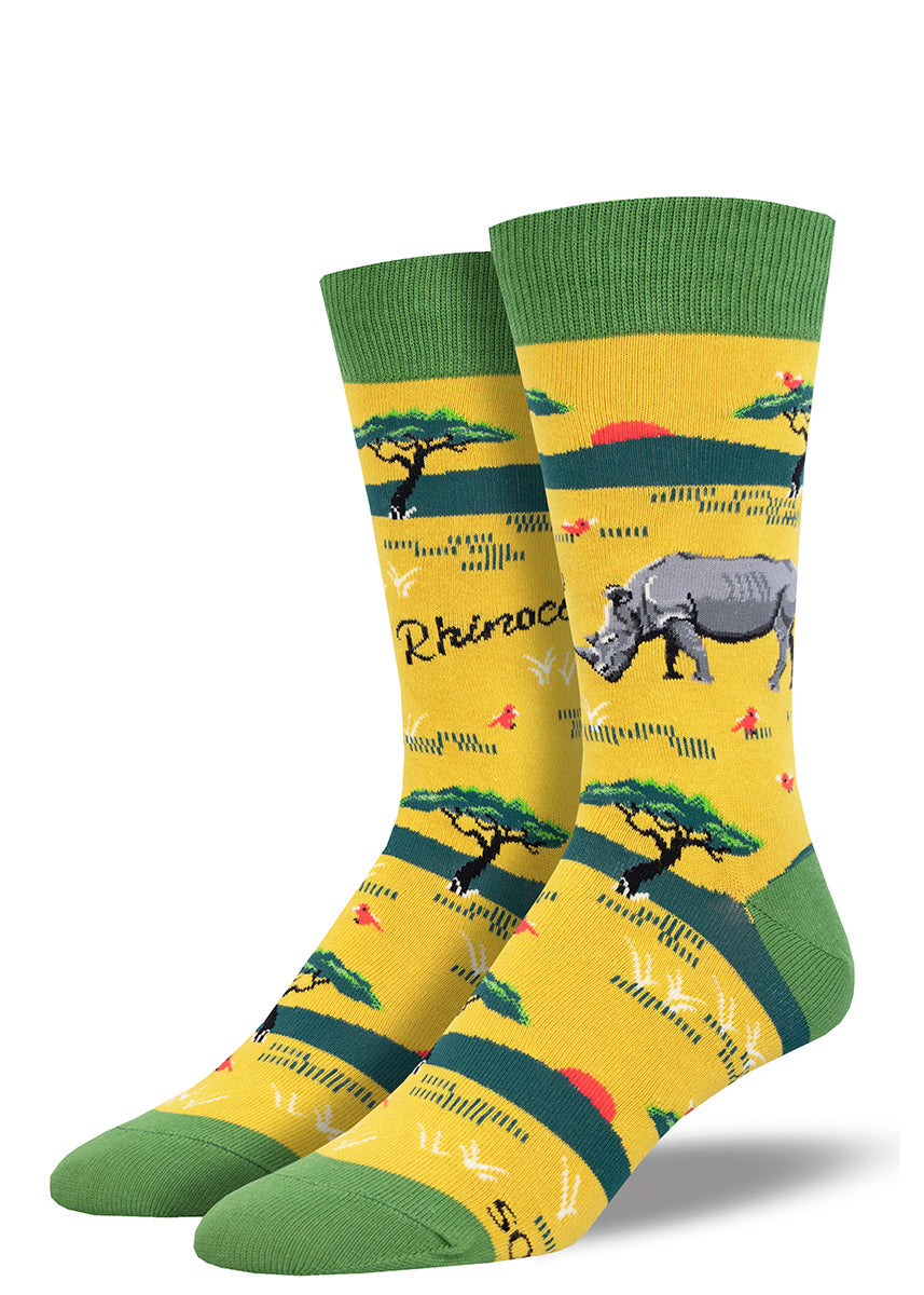 Men's crew socks featuring a design of a Rhinoceros hanging out in field with a bunch of small red birds, on a gold background with green accents.