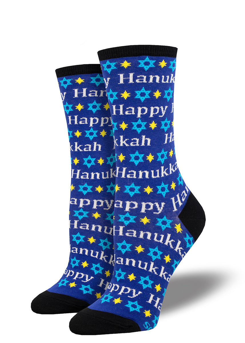 Blue novelty holiday crew socks for women featuring a repeating pattern of the Star of David and the words "Happy Hanukkah" written in silver.