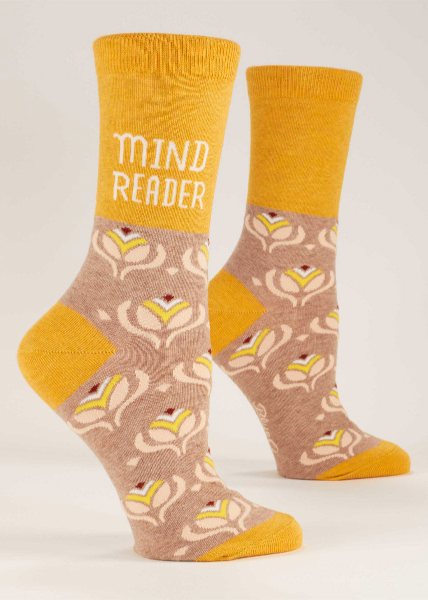 Yellow and beige crew socks for women that say &quot;MIND READER&quot; on them and have a repeating abstract floral pattern.