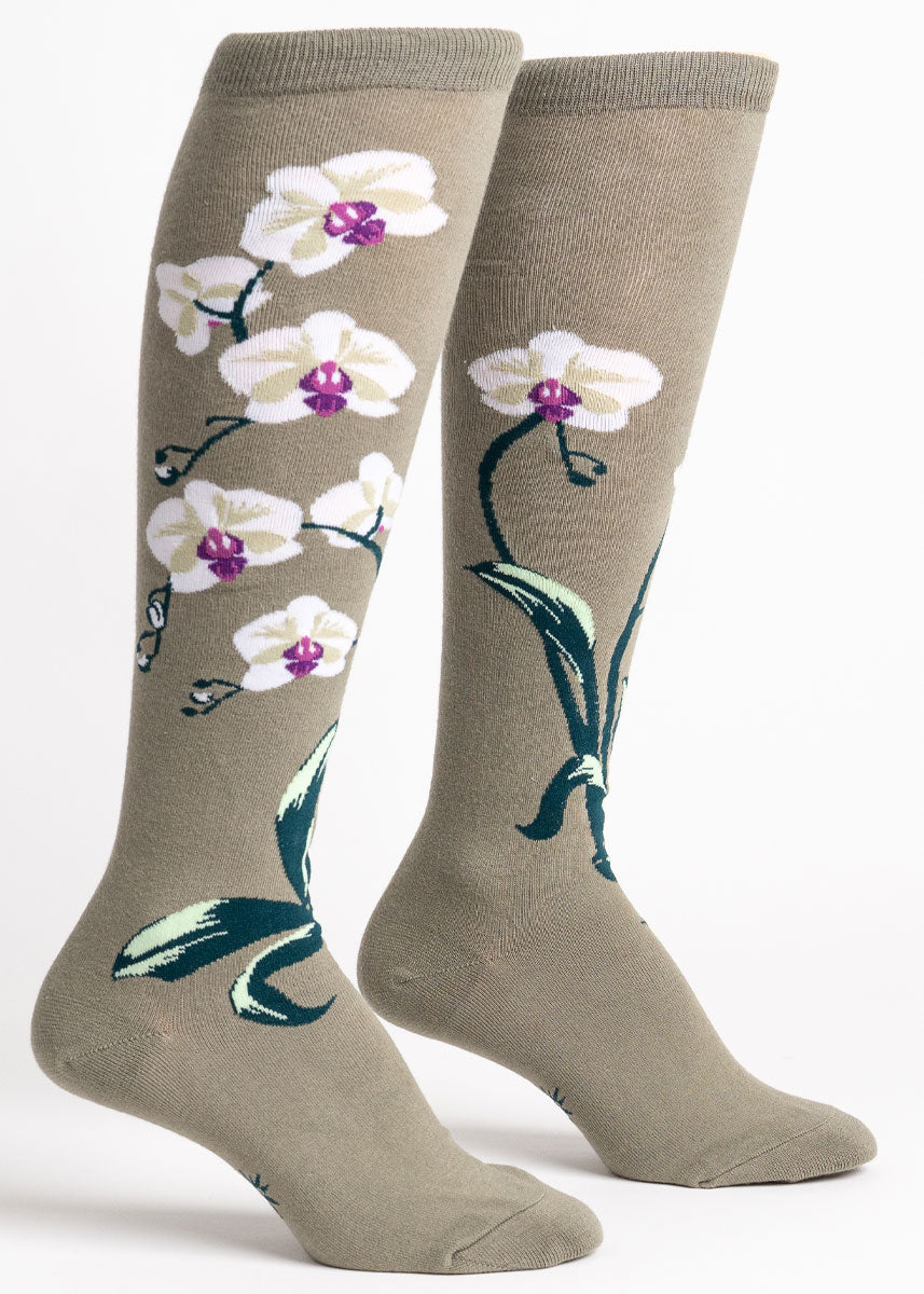 Muted green knee socks for women that show an orchid with multiple white and purple blooms and a dark green stem and leaves blooming up the entire leg.