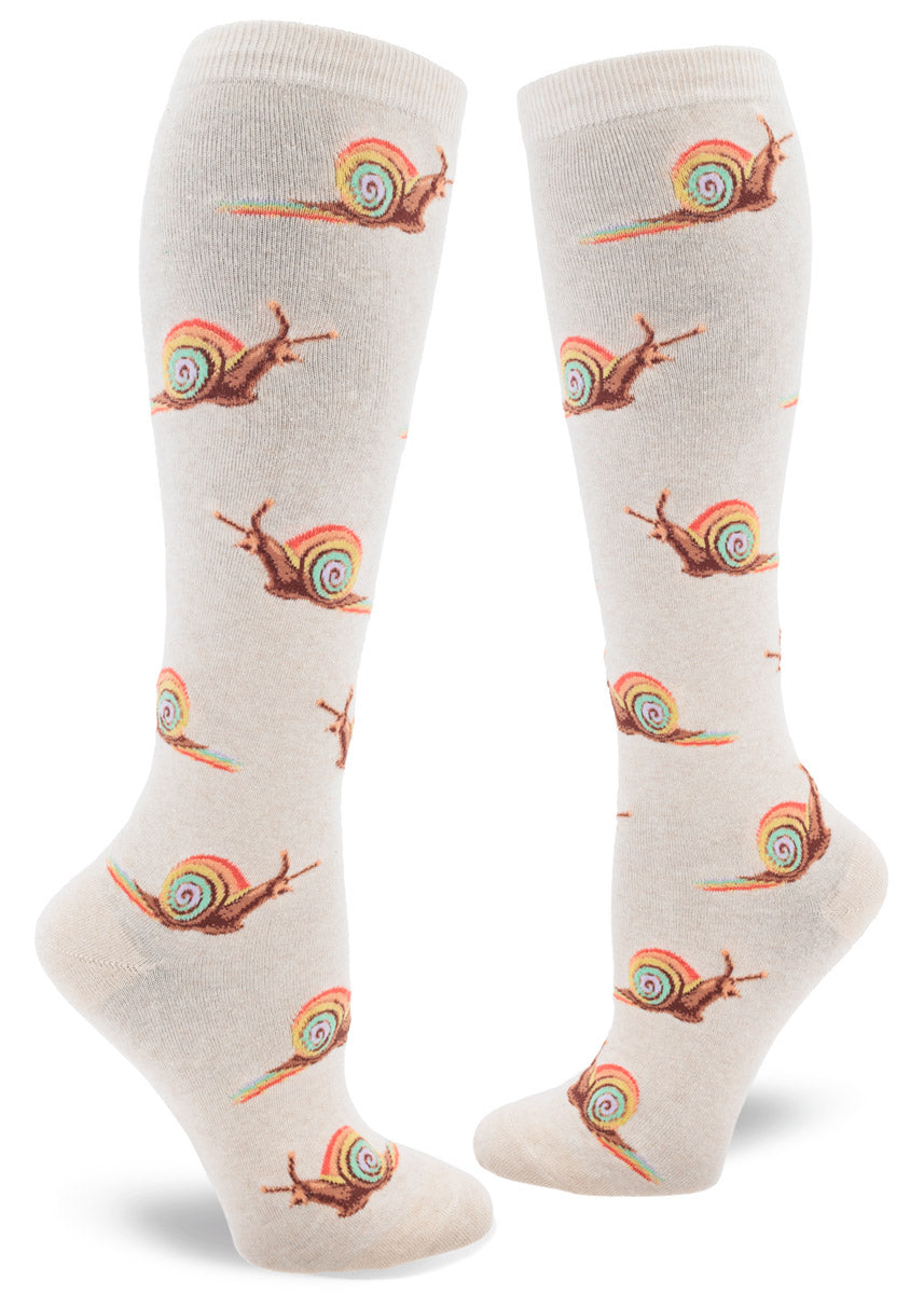 Cream knee socks for women with an allover pattern of brown snails with pastel rainbow shells leaving a rainbow slime trail behind them.