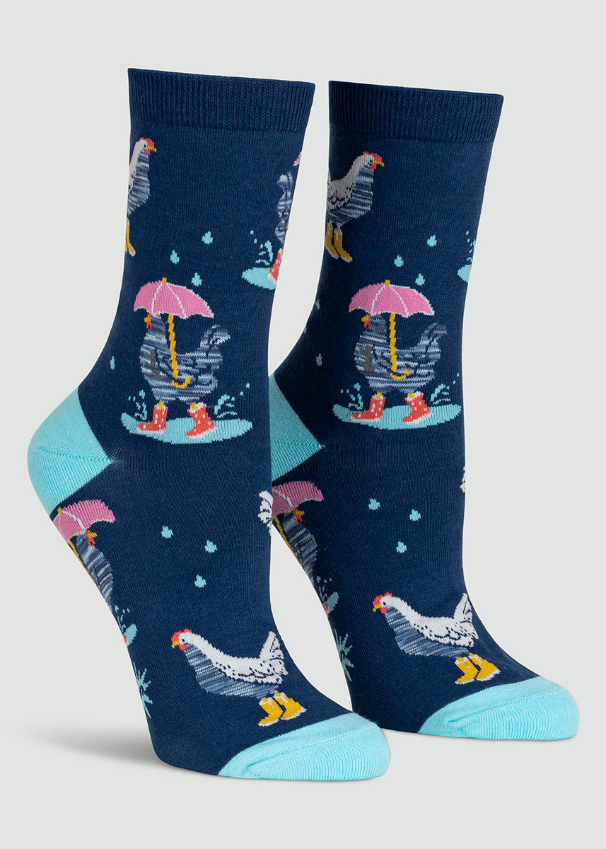 Navy crew socks for women featuring raindrops and chickens wearing rain boots and splashing in puddles, with some also holding umbrellas.