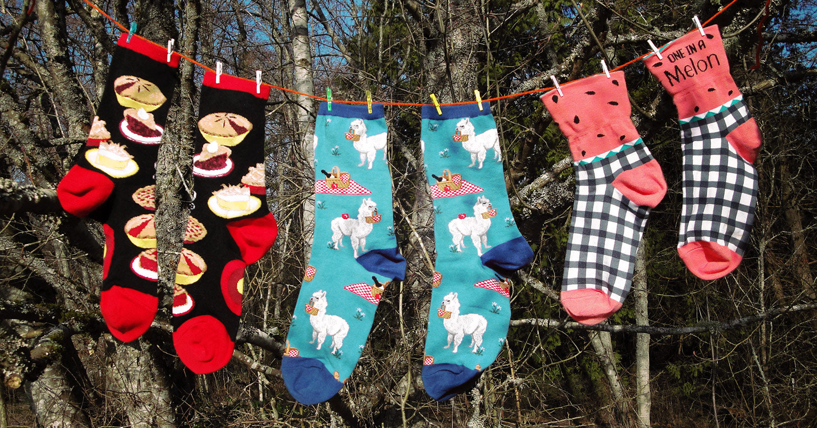 Novelty socks with patterns including food and animals hang on a clothesline to dry after being washed.