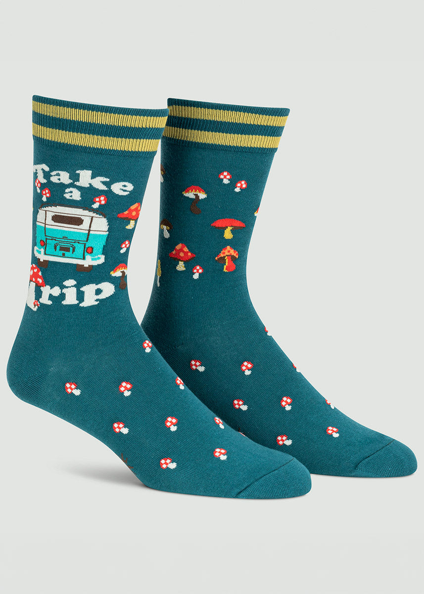Dark teal socks for men featuring the back of a blue camper van surrounded by the words &quot;Take a Trip&quot; against a background of red mushrooms.