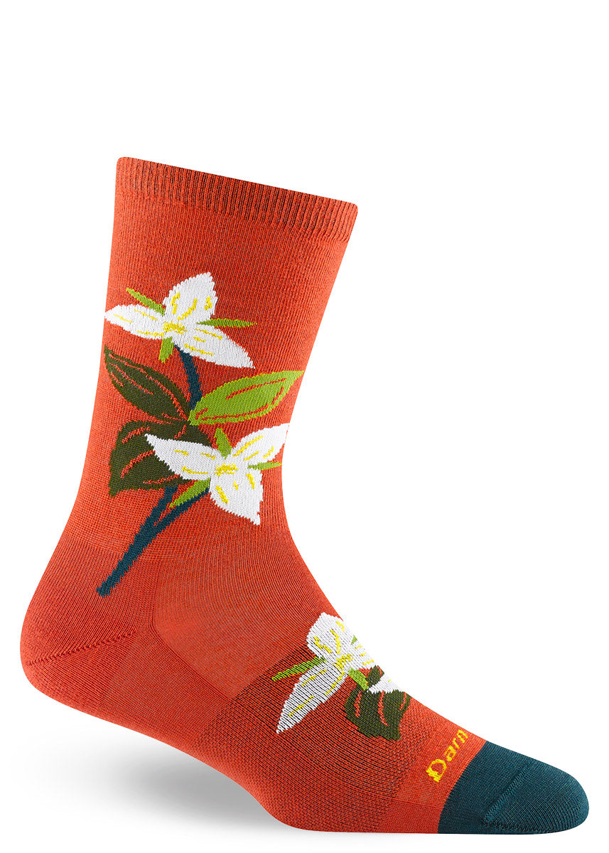 Women&#39;s merino wool crew socks with white trillium flowers on a tomato red background.
