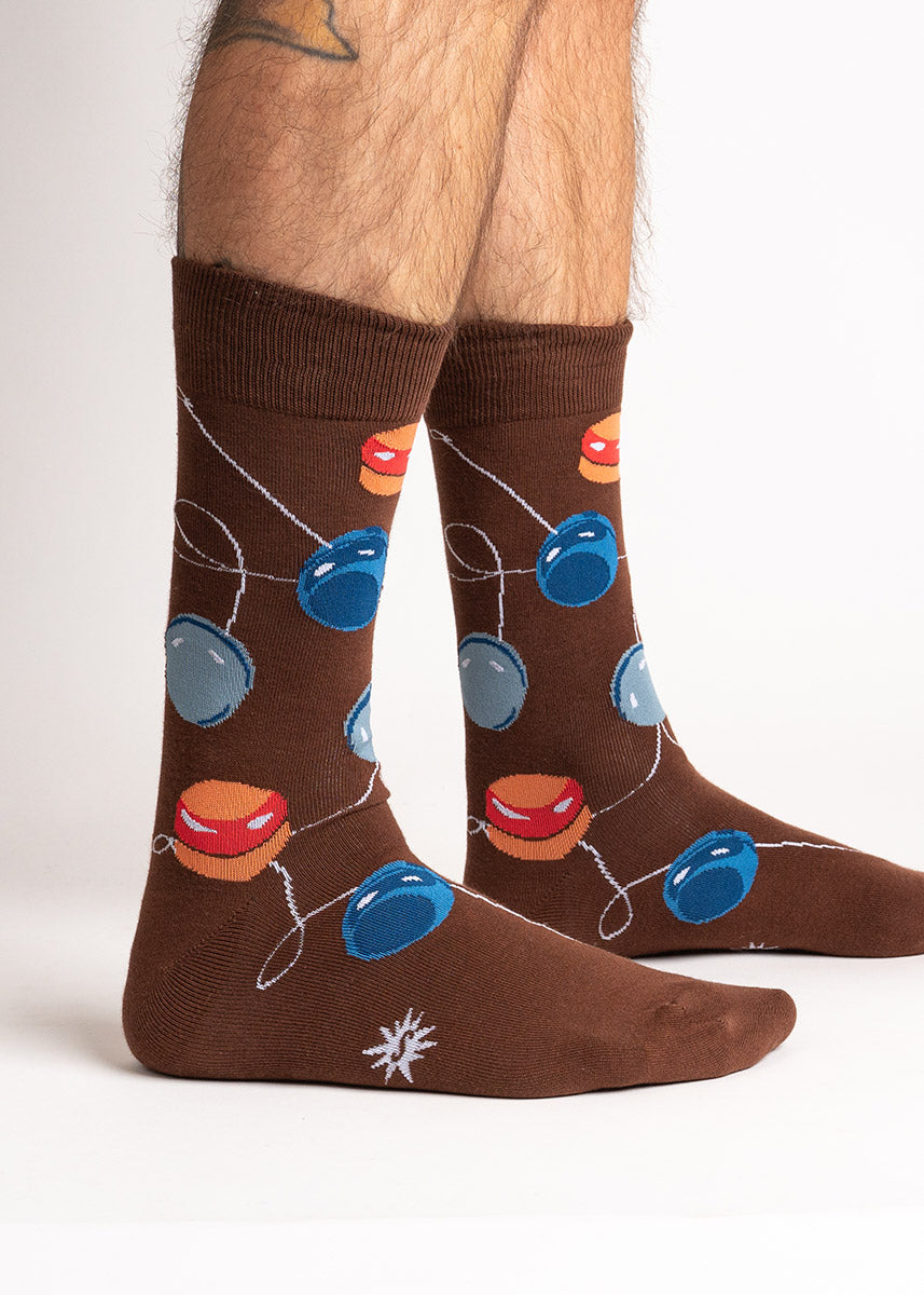 Brown crew socks for men with an allover pattern of yo-yos in shades of blue, orange, and gray.