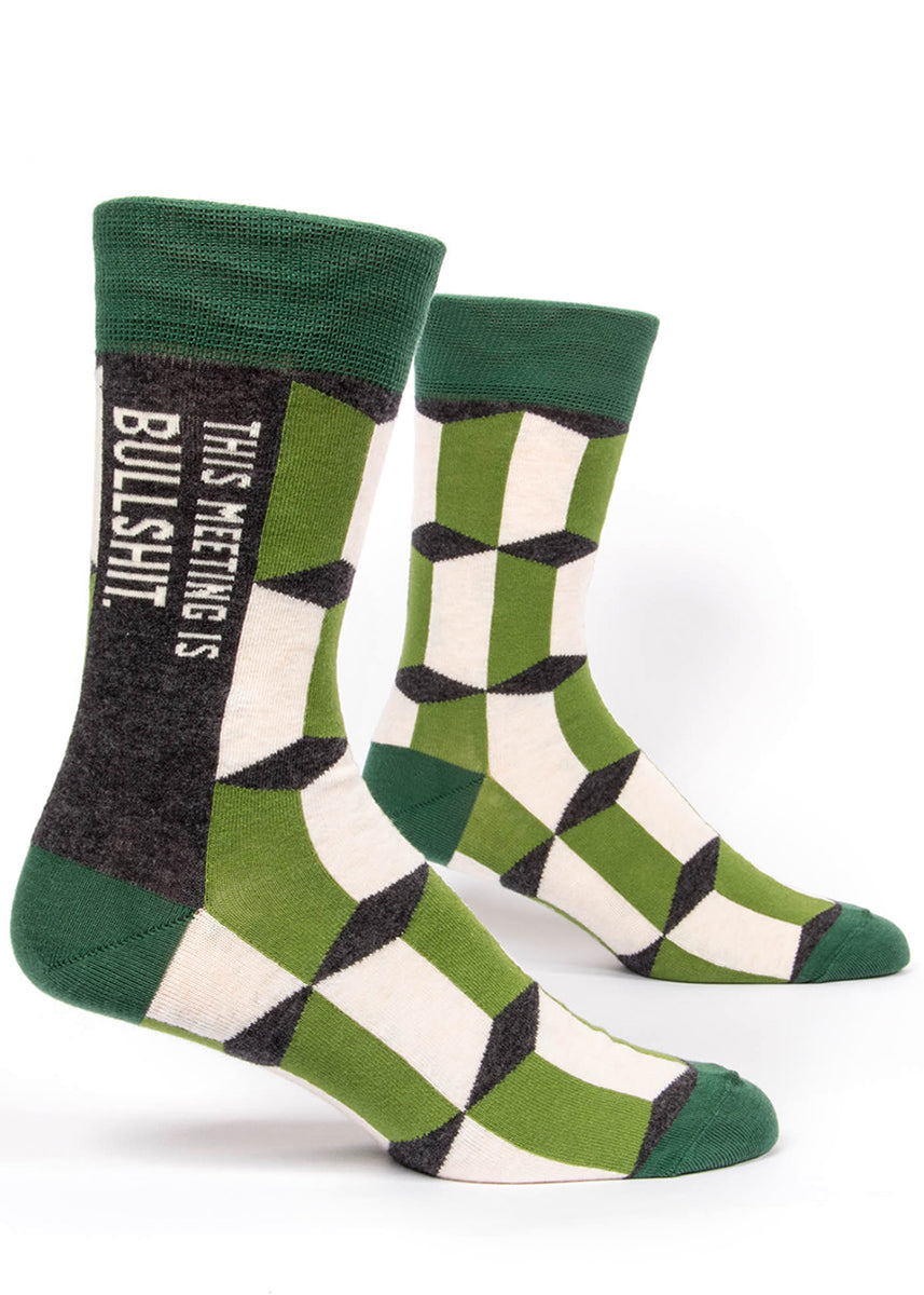 Funny swear word men&#39;s socks that say &quot;This Meeting is Bullshit&quot; on a green patterned background.