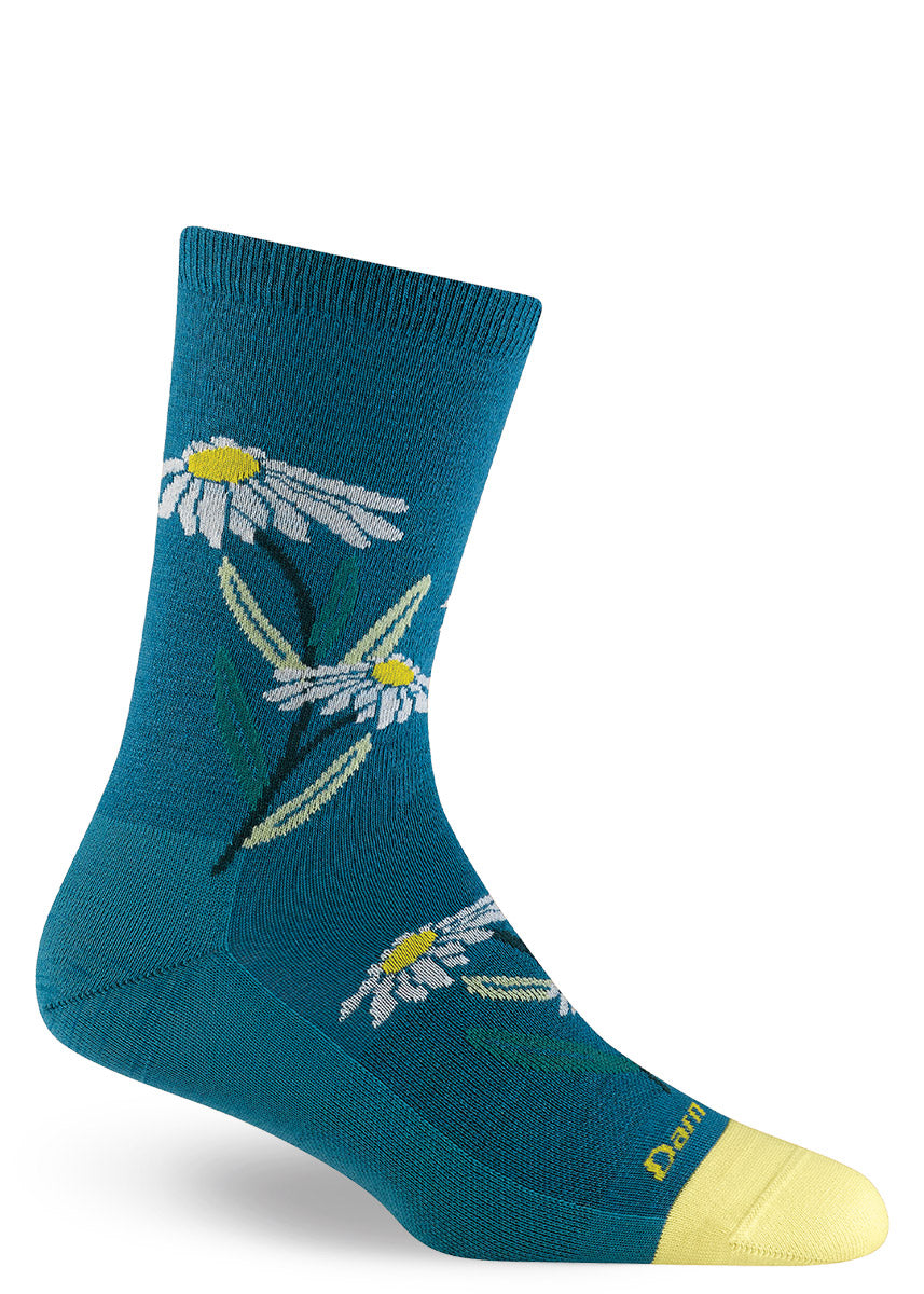 Wool crew socks with white and yellow daisies on a teal blue background with the toe tipped in a matching yellow hue.