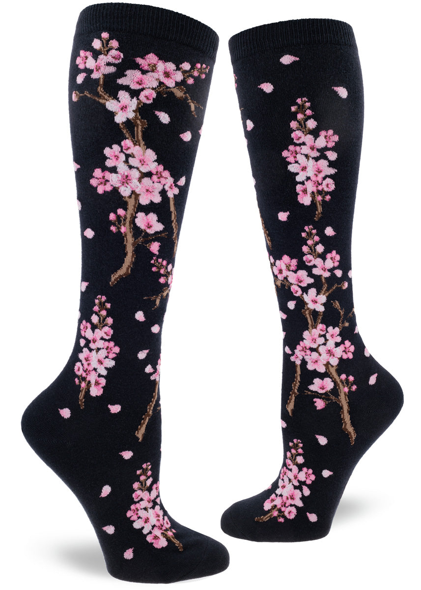 Knee high socks for women feature vibrant pink cherry blossoms on a dark navy background.
