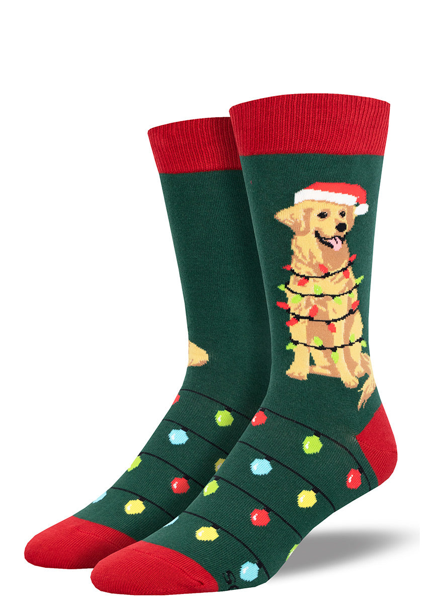 Green men&#39;s crew socks with red accents show a golden retriever dog wearing a Santa hat while wrapped in a string of Christmas lights on the leg, with additional multicolored lights adorning the foot.