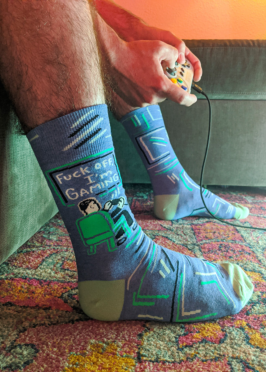 Swear-word socks for men show a guy playing video games with the words, &quot;Fuck off, I&#39;m gaming.&quot;