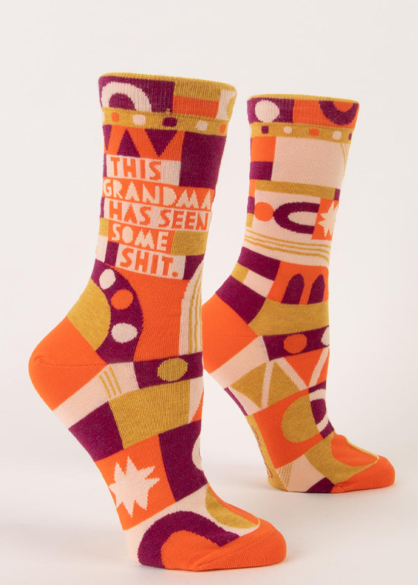Funny crew socks for women say "This Grandma Has Seen Some Shit" and feature zany patterns in orange, magenta, mustard, and light pink!