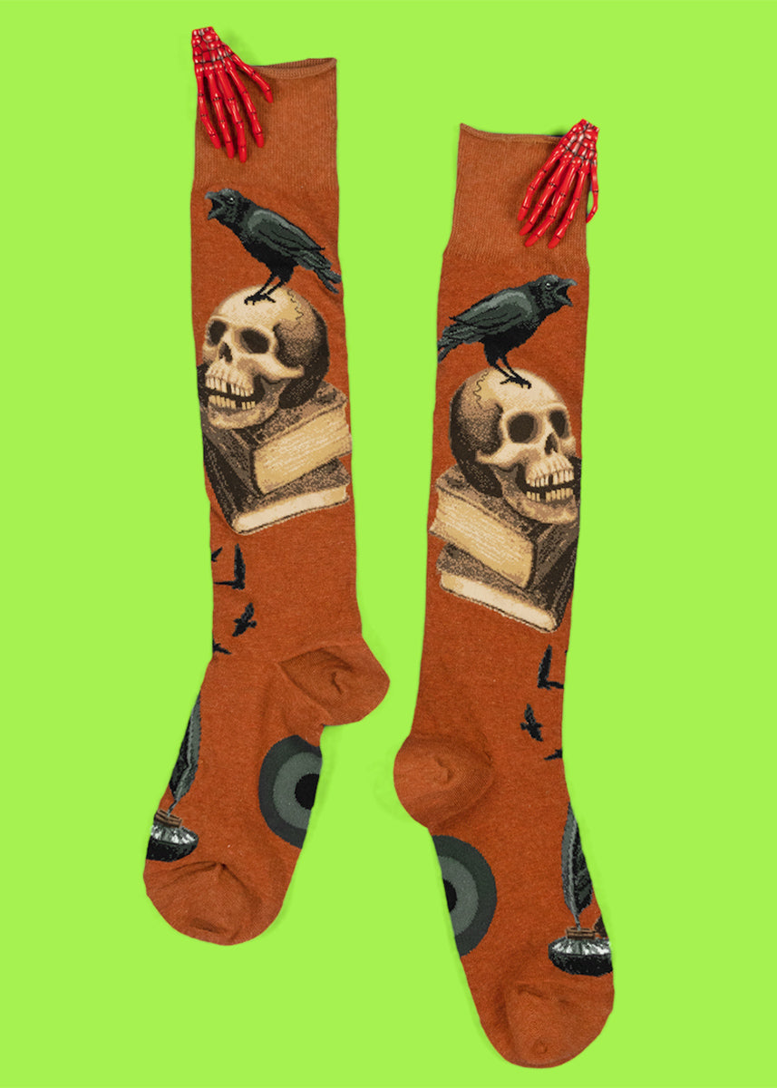 Knee socks inspired by Edgar Allen Poe feature ravens, human skulls, antique books and feather pens.