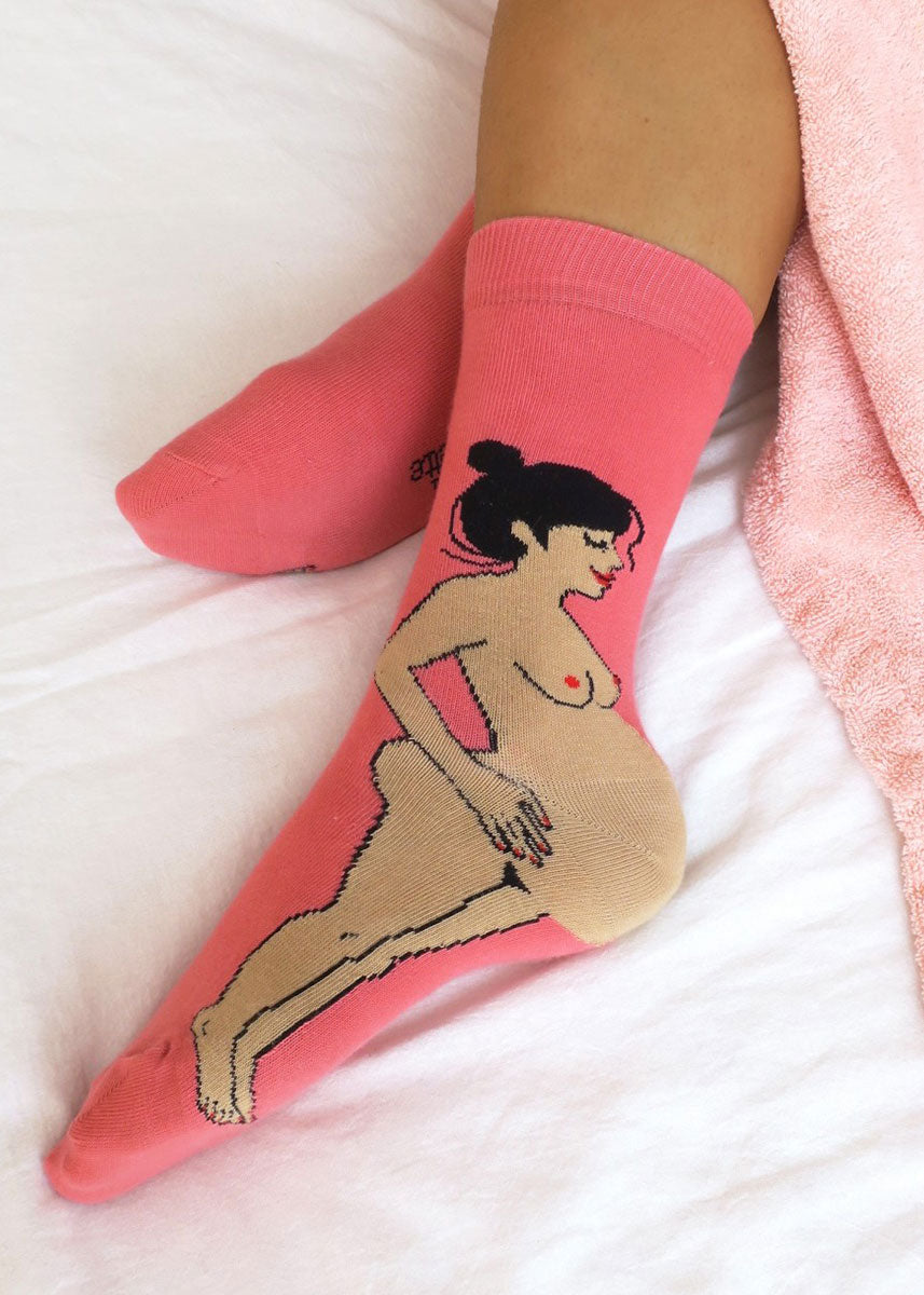 Funny pregnancy socks show a nude pregnant women with olive skin and black hair, with her bulging belly forming the heel of the socks.