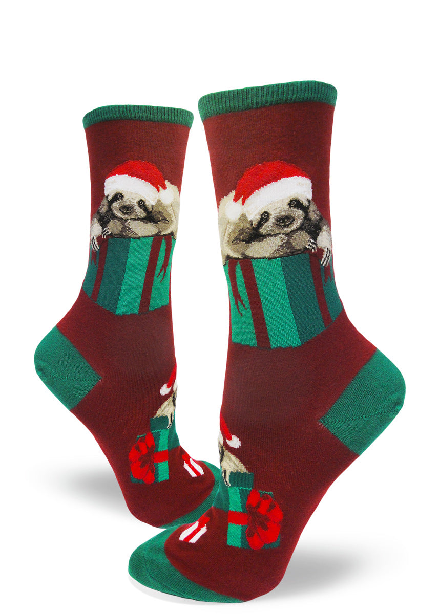 Cute Christmas sloth socks for women with sloths in Santa hats laying on Christmas presents with a dark red background