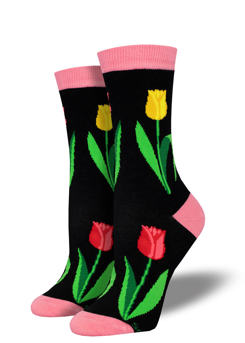 Black crew socks accented with pink at the heel, toe and cuff, featuring a pattern of yellow and red tulip flowers.