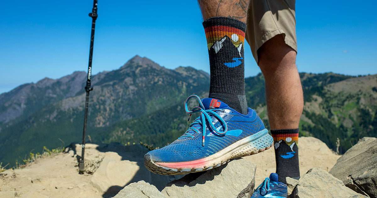 A man in mountain-themed wool hiking socks hikes a mountain trail in Port Angeles, Wash.
