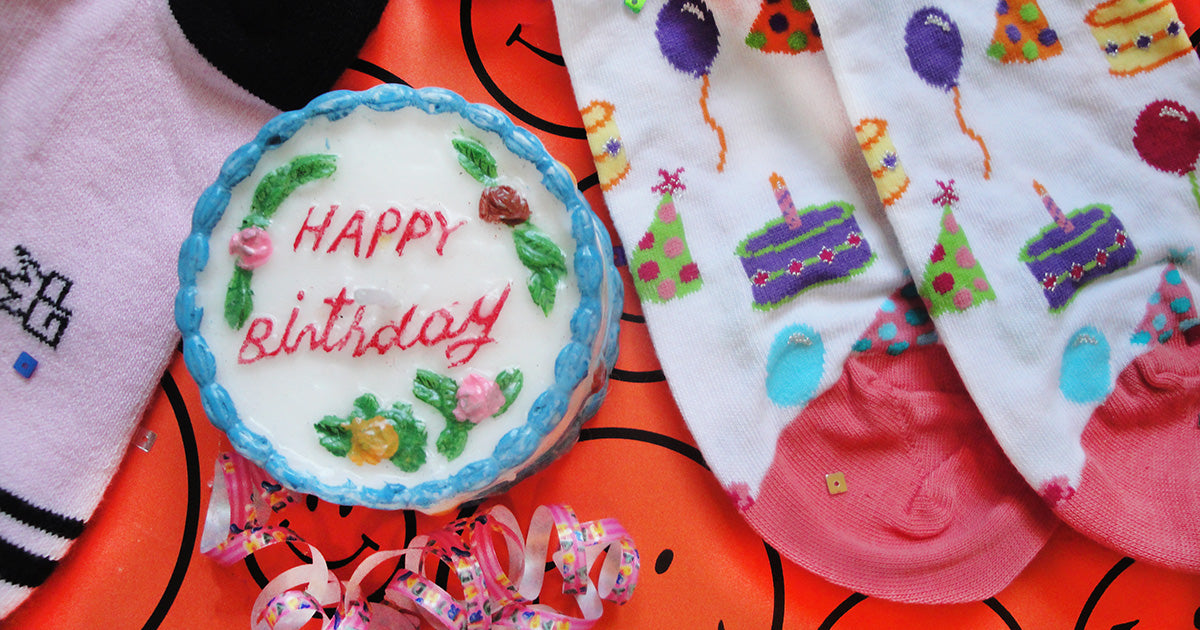 Cute birthday socks beside a mini birthday cake-shaped candle
