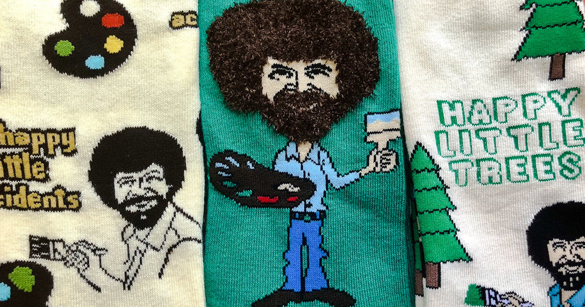 Bob Ross sock styles in cream and green featuring the PBS artist and icon with his paintbrush, palette and signature hair.