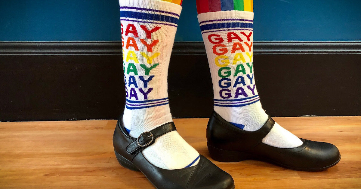Gay socks with the word "GAY" repeated in rainbow letters on white unisex socks