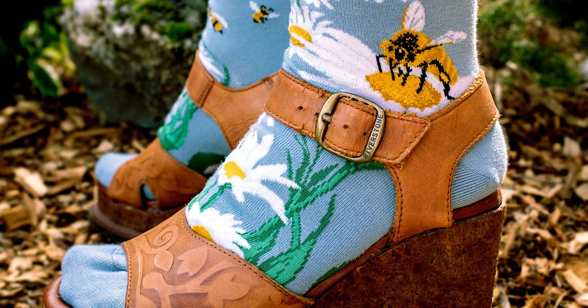 Bee socks with daisies and honeybees paired with brown floral embossed leather platform wedge sandals for a hippie-inspired look.
