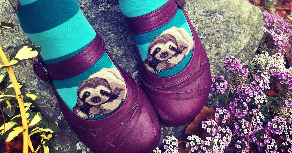 Cute sloth socks peep over the toes of magenta shoes