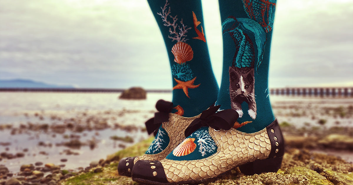 Cat mermaid socks with a design of cats with mermaid tails in teal. 