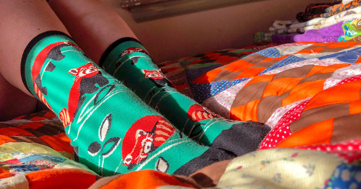 Woman wearing red panda socks in bed.