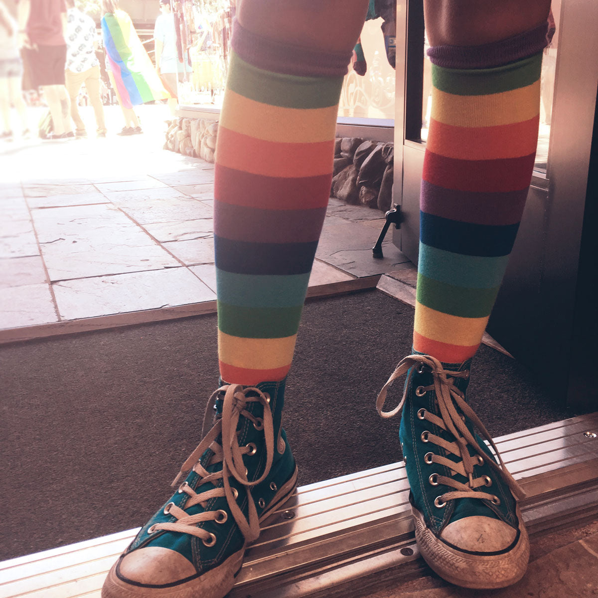 Take every step with pride in a pair of knee-high rainbow-striped socks, shown here worn with green Converse sneakers.