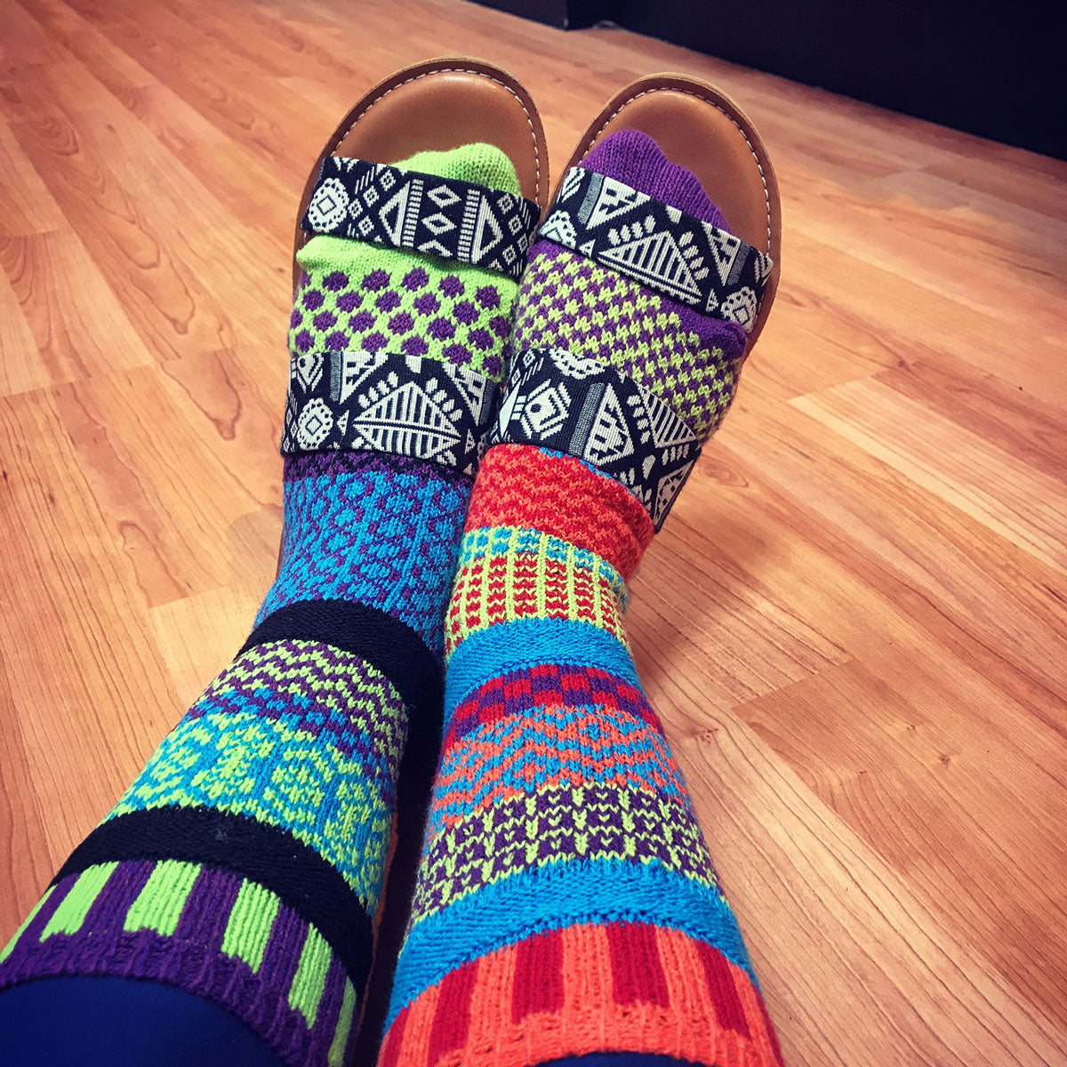 Solmate socks are colorful mismatched socks made in the USA from recycled cotton, as shown here in a geometric knit pattern in a rainbow of bright colors.