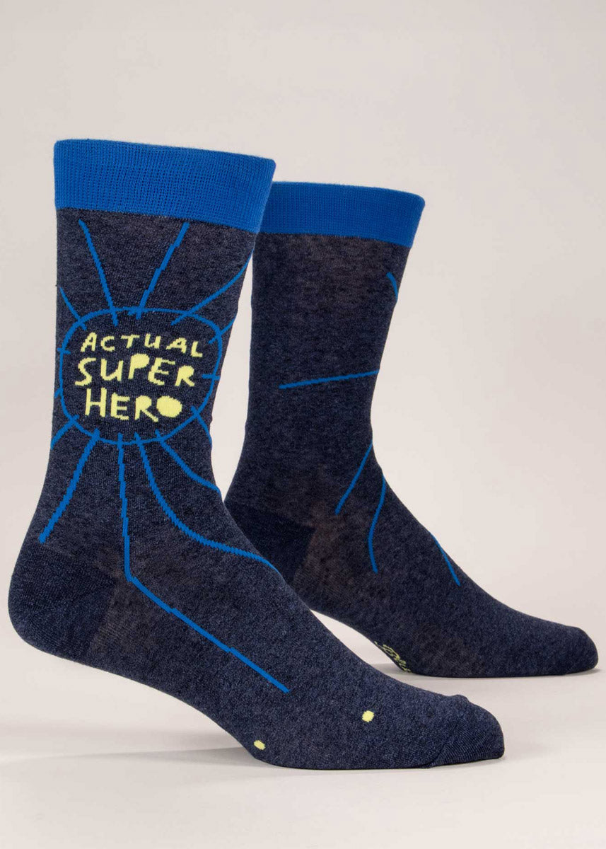 Navy men&#39;s crew socks that say “Actual Super Hero&quot; in yellow on the leg with abstract doodle embellishments in blue.