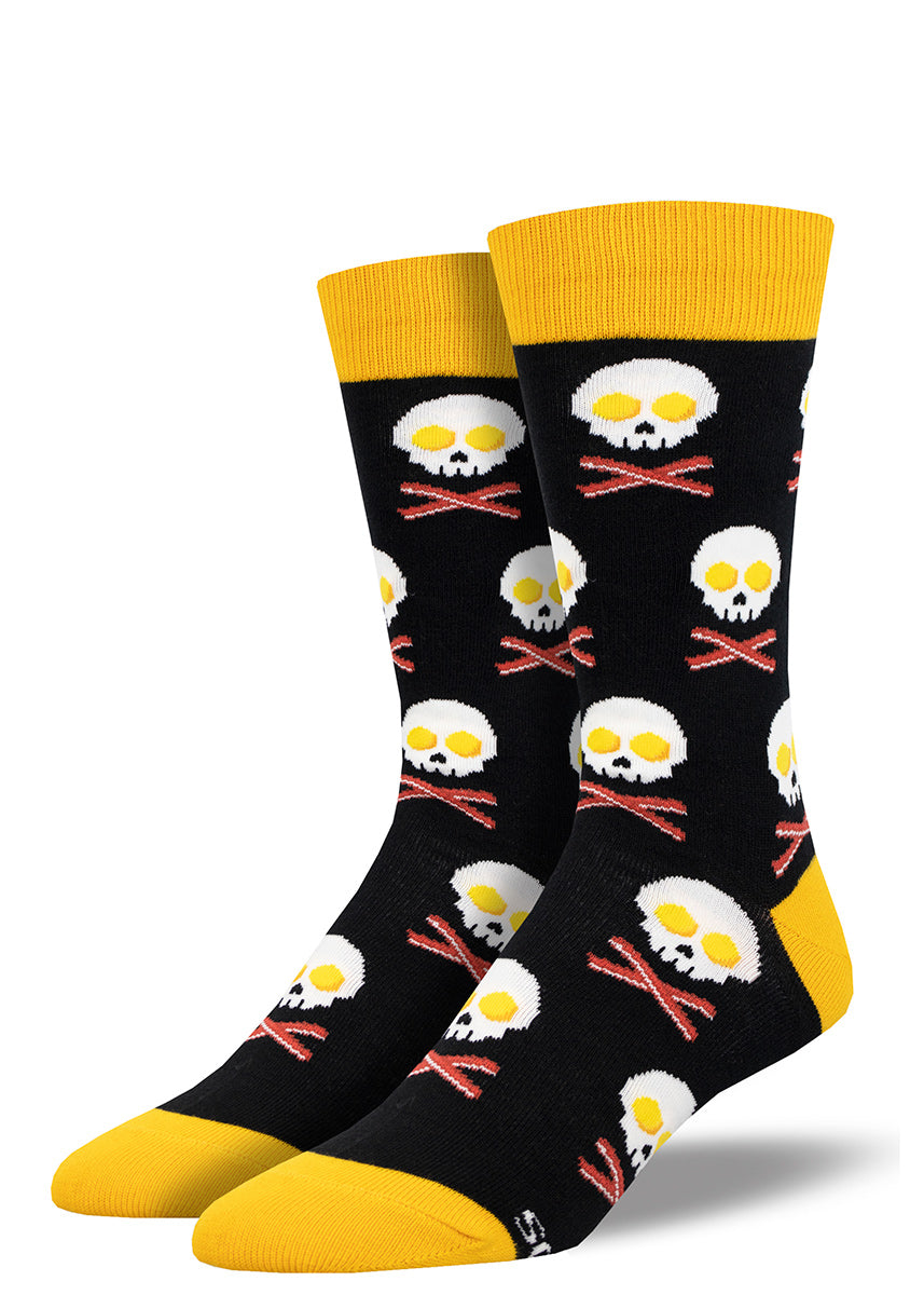 Men&#39;s crew socks in black with yellow accents feature a repeating patten of eggs and bacon strips arranged to look like a skull and crossbones.