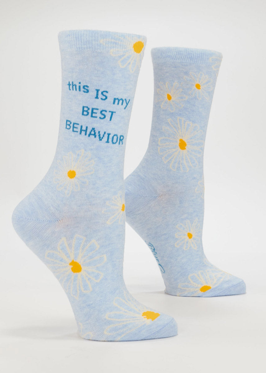Light blue women's crew socks with daisy flowers and "this IS my BEST BEHAVIOR" text on a white background.