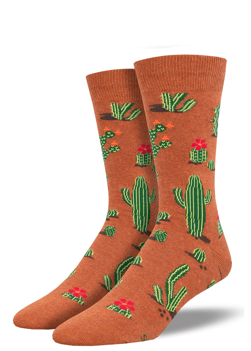 Novelty cactus socks for men have a rust background embellished with green desert cacti and bright red cactus flowers.