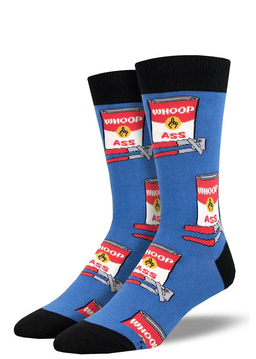 Funny men&#39;s novelty crew socks feature a repeating pattern of nostalgic red-and-white soup cans, each with the words &quot;Whoop Ass&quot; on them, and red can openers, all on a blue background.
