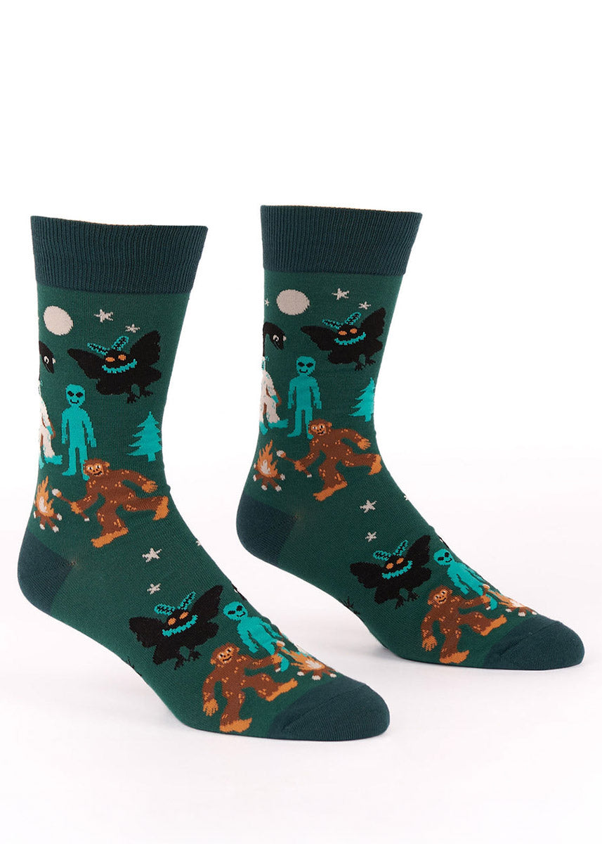 Pair of green crew socks with aliens, Yeti, Mothman, Bigfoot and Loch Ness monster designs.