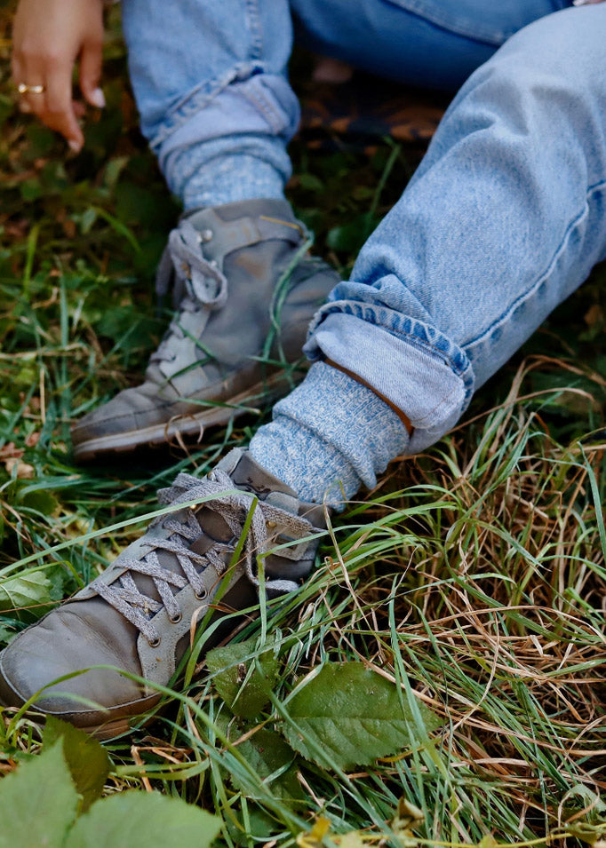 A model wears blue slouchy slub-knit crew socks with jeans and gray casual athletic-inspired shoes.