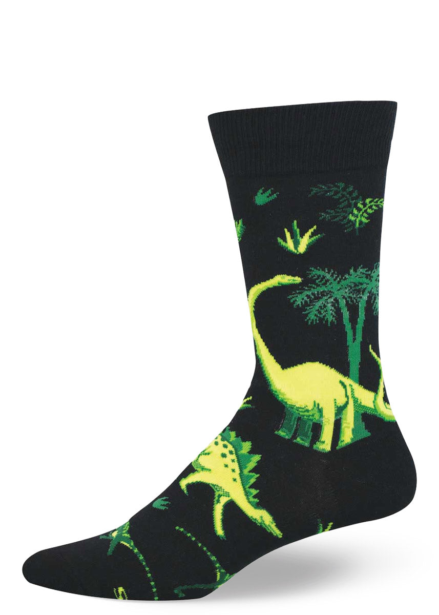 Black crew sock with green dinosaur and jungle plant pattern on a white background.
