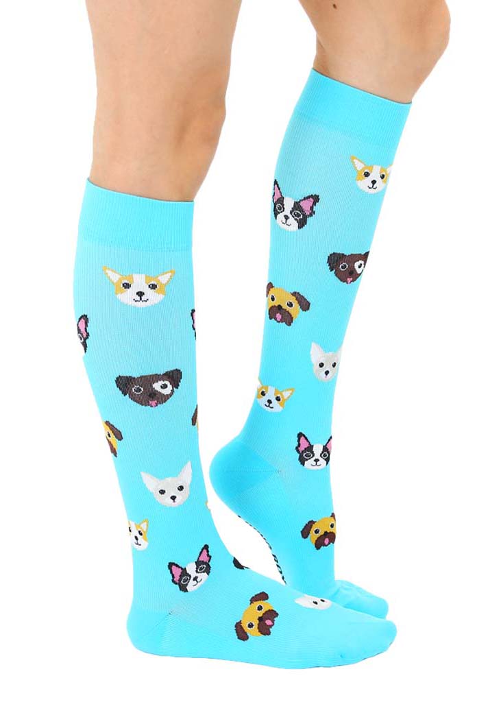 Side view of blue knee-high compression socks with an allover pattern of various dog faces, including Boston terriers, Corgis, Chihuahuas and more.